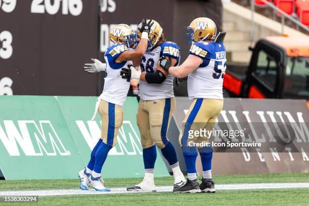Winnipeg Blue Bombers wide receiver Nic Demski celebrates his touchdown with offensive lineman Geoff Gray and offensive lineman Patrick Neufeld...