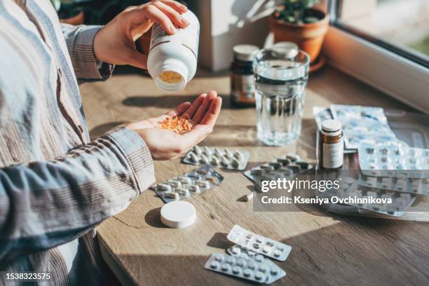 closeup female hand neatly placing medicament at domestic first aid kit top view. storage organization in transparent plastic box drug, pill, syringe, bandage. fast health help safety emergency supply - drugs stock pictures, royalty-free photos & images