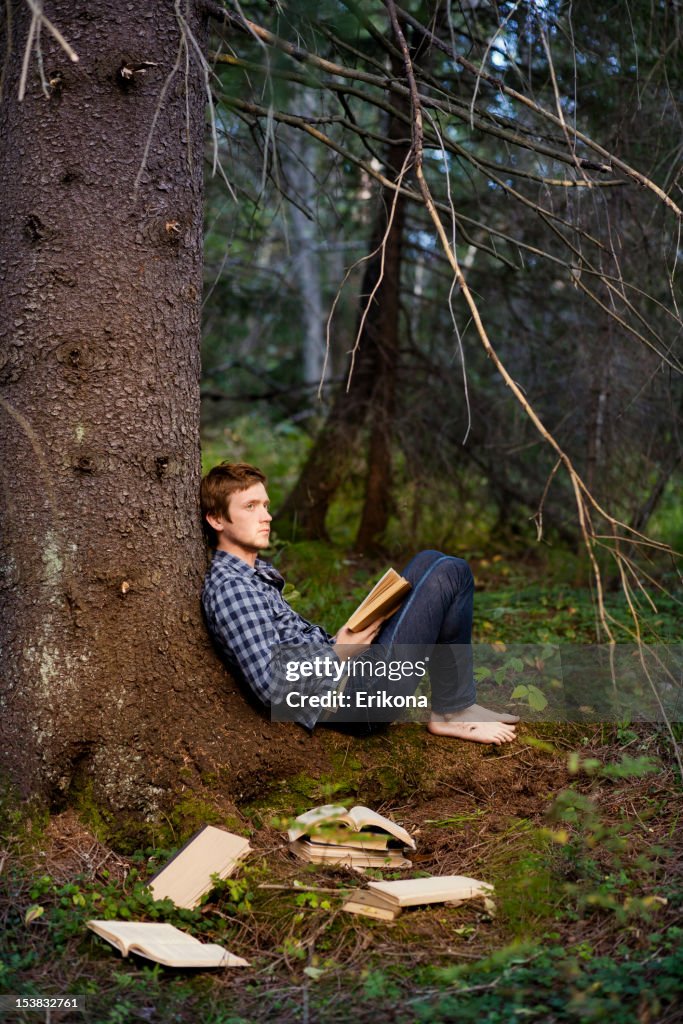 Young Men Reading Book in Dark Forest