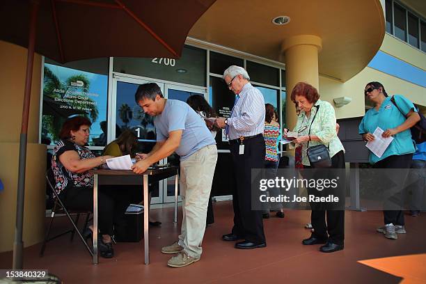 People stand in line to deliver their voter registration forms to a Miami-Dade Elections Department officials on the final day for voters to register...