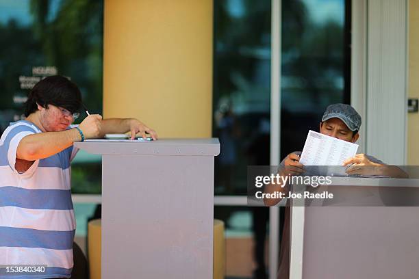 Allan Banojakedjian and Jesus Romero fill out their voter registration forms at the Miami-Dade Elections Department on the final day for them to...