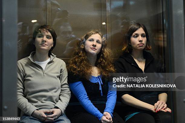 Members of the all-girl punk band "Pussy Riot" Maria Alyokhina, Yekaterina Samutsevich and Nadezhda Tolokonnikova sitting in a glass-walled cage in...
