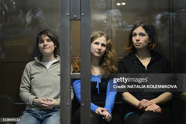 Members of the all-girl punk band "Pussy Riot" Maria Alyokhina, Yekaterina Samutsevich and Nadezhda Tolokonnikova sit in a glass-walled cage in a...