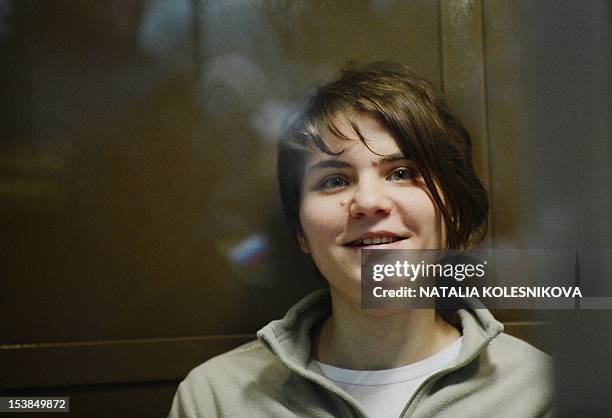 One of the jailed members of the all-girl punk band "Pussy Riot," Yekaterina Samutsevich, smiles while sitting in a glass-walled cage in a court in...