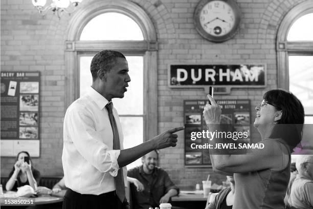 President Barack Obama poses for a woman to take his picture at a local restaurant in Durham, New Hampshire, on June 25, 2012. Obama has opened up a...