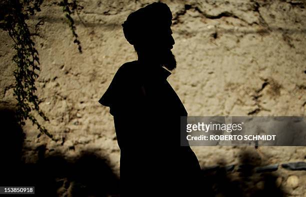 An Afghan villager stands in the shade next to an adobe wall in the small town of Baharak in the province of Badakhshan on October 6, 2012. The town...