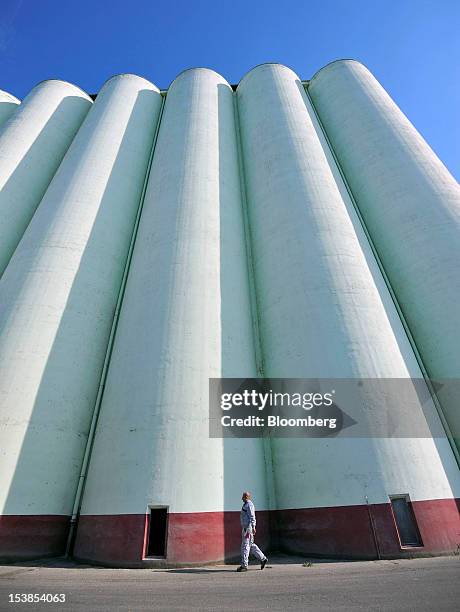 An employee passes silos for wheat and corn grain at Granexport AD port, part of MK Group, on the Danube river in Pancevo, Serbia, on Tuesday, Oct....