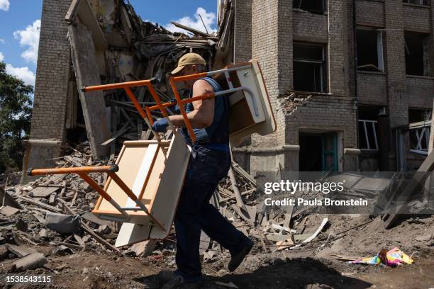 Workers carry school desks out from classrooms after the overnight rocket attack of School number 16 which was empty at the time of the attack on...