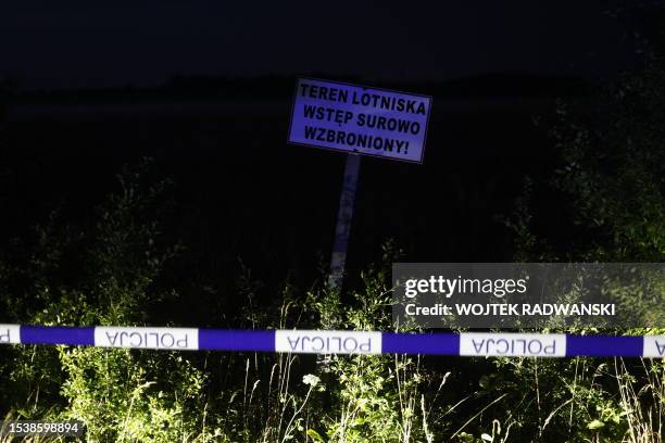 Police cordon is displayed near a sign reading "access to the airport area strictly forbidden", after a Cessna 208 small plane crashed into an hangar...