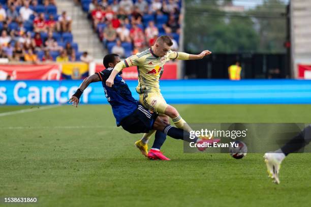 Alvas Powell of FC Cincinnati tackles the ball from Cameron Harper of the New York Red Bulls during the first half at Red Bull Arena on July 12, 2023...