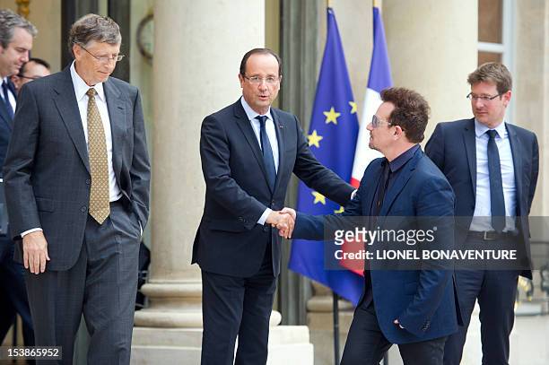 Irish musician and humanitarian activist Bono shakes hands with French President Francois Hollande next to Microsoft co-founder turned global...