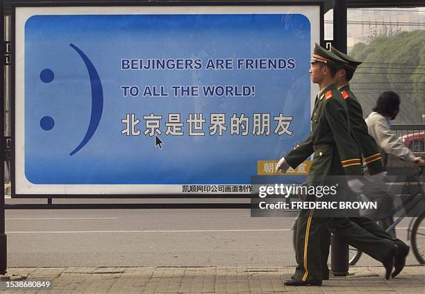 Military soldiers march past a "happy face" billboard in Beijing, 22 October 2001. With the recent hosting of the Asia Pacific Economic Cooperation...