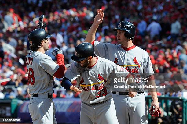 Pete Kozma of the St. Louis Cardinals celebrates with teammates Daniel Descalso and David Freese after hitting a three run home run in the second...