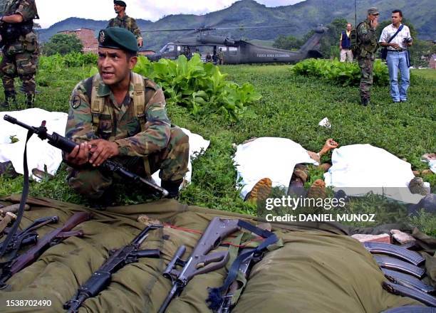 Soldier holds a gun near the bodies of five guerrillas from the Revolutionary Armed Forces of Colombia in San Carlos, 120kms east of Medellin,...