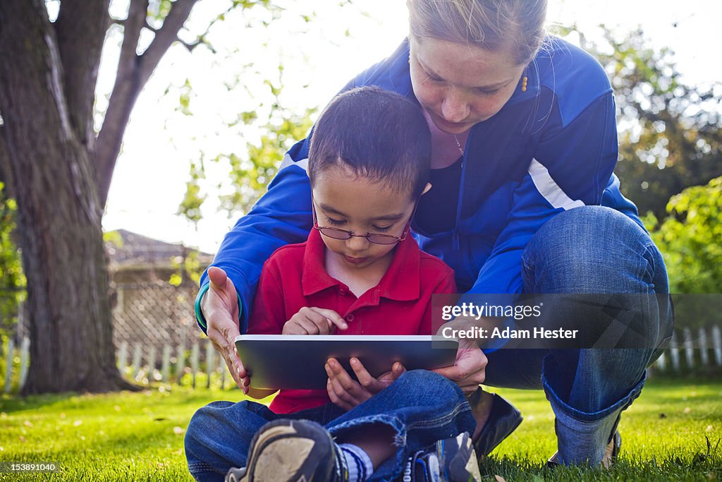 A young woman and boy using a tablet PC outdoors