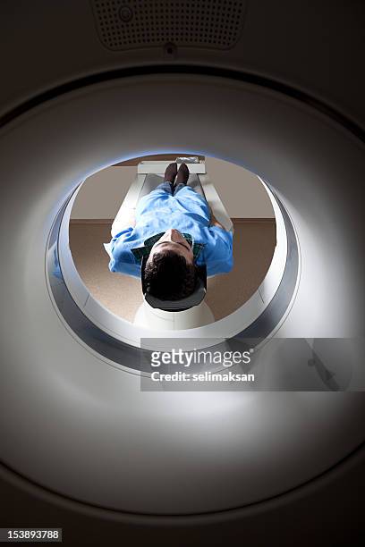 hombre tener un examen médico a través del escáner de gato - mri machine fotografías e imágenes de stock