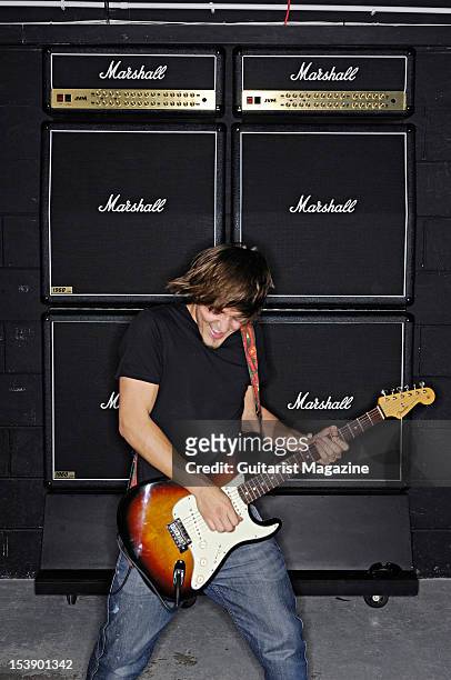 Guitarist playing a Fender Stratocaster electric guitar in front of a stack of Marshall electric guitar amplifiers, during a studio shoot for...