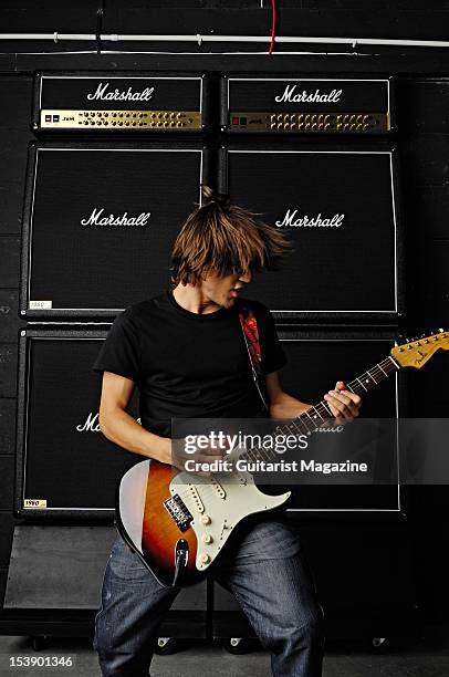 Guitarist playing a Fender Stratocaster electric guitar in front of a stack of Marshall electric guitar amplifiers, during a studio shoot for...