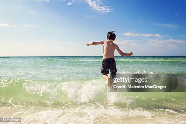 boy jumping over waves - festin stock-fotos und bilder