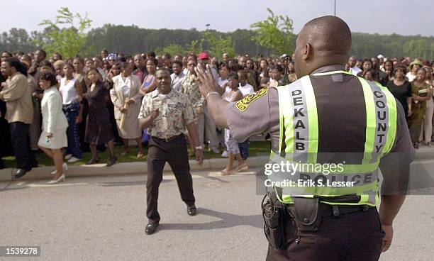 Dekalb County Police officer tries to control the thousands of fans waiting in line to attend the public funeral of singer Lisa "Left Eye" Lopes at...