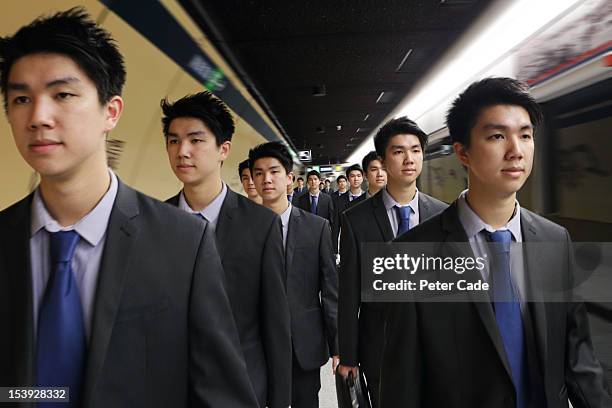 identical men in suits walking along platform - cloning stock-fotos und bilder