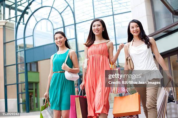 best female friends shopping - a woman carrying a shopping bag walks out of a mall in beijing stock-fotos und bilder