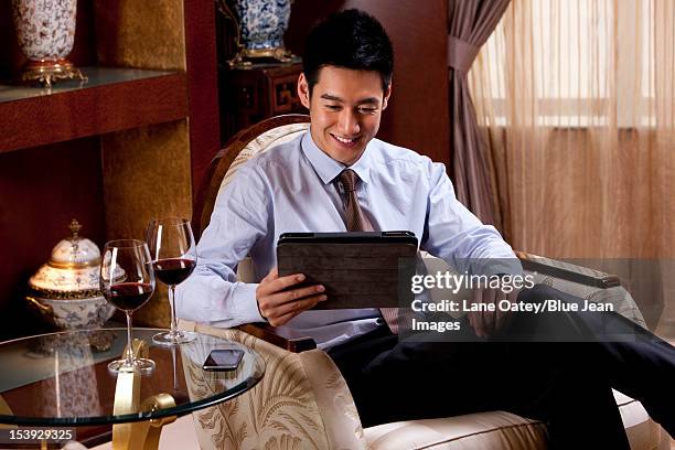 young businessman using digital tablet in hotel - man in suite holding tablet stockfoto's en -beelden