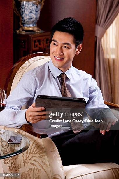 young businessman using digital tablet in hotel - man in suite holding tablet stockfoto's en -beelden