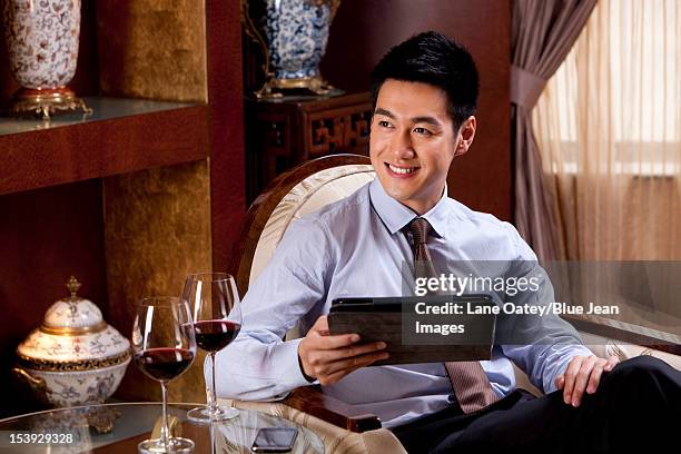 young businessman using digital tablet in hotel - man in suite holding tablet stockfoto's en -beelden