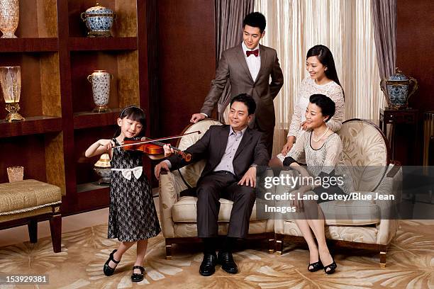 little girl playing violin in front of family members - violin family stock pictures, royalty-free photos & images