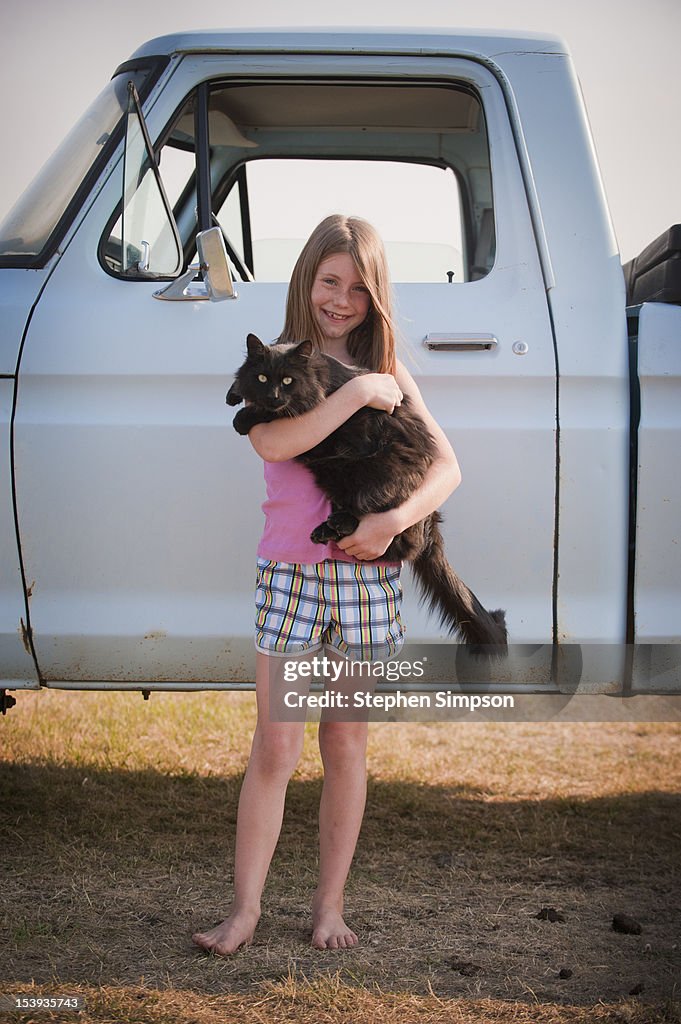 Farm girl with her pet cat and pick up truck