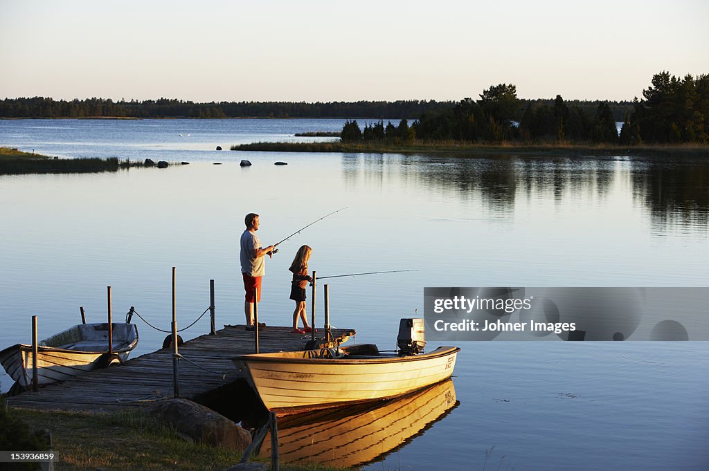 Father and daughter fishing from a jetty, Sweden.