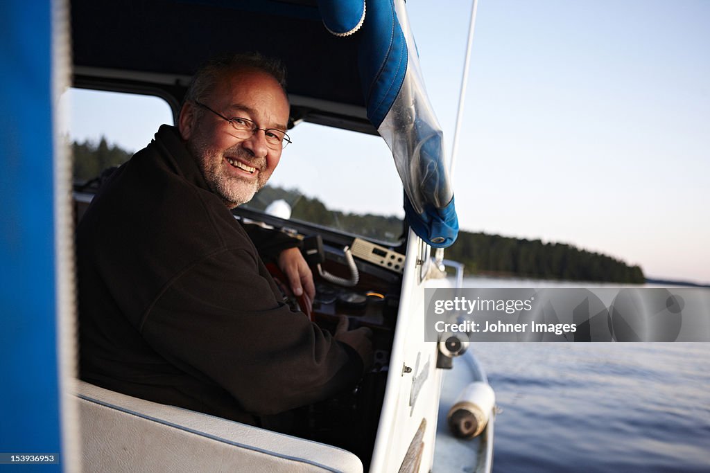 Man driving boat, smiling