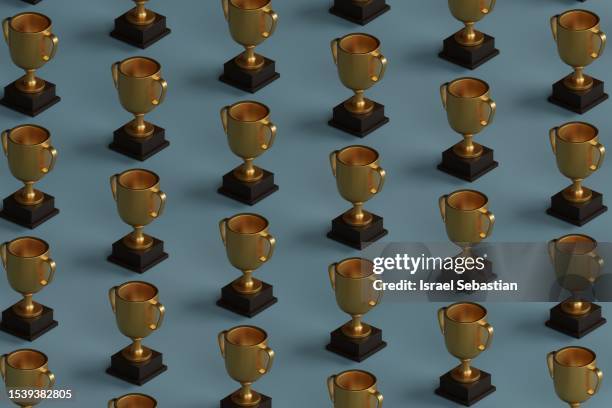 pattern of gold trophies placed in a line on a blue plain background. - gold patina stock pictures, royalty-free photos & images