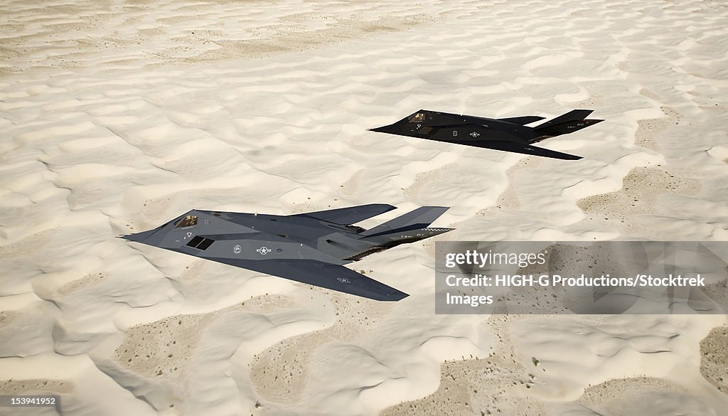 Two F-117 Nighthawk stealth fighters fly on a training sortie out of Holloman Air Force Base, New Mexico, over the White Sands National Monument.