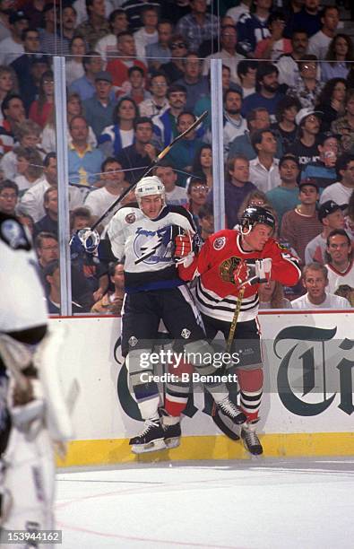 Jeremy Roenick of the Chicago Blackhawks checks Roman Hamrlik of the Tampa Bay Lightning into the boards during an NHL game circa 1993 at the Expo...