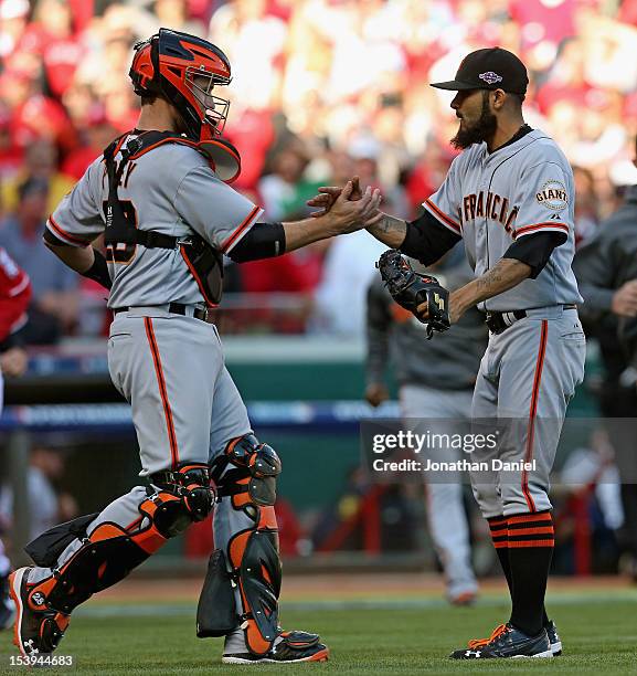 Buster Posey and Sergio Romo of the San Francisco Giants shake hands after a win against the Cincinnati Reds in Game Five of the National League...