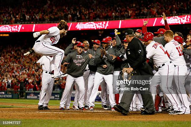 Jayson Werth of the Washington Nationals celebrates with his teammates as he jumps on home plate to score on his solo game-winning walk-off home run...