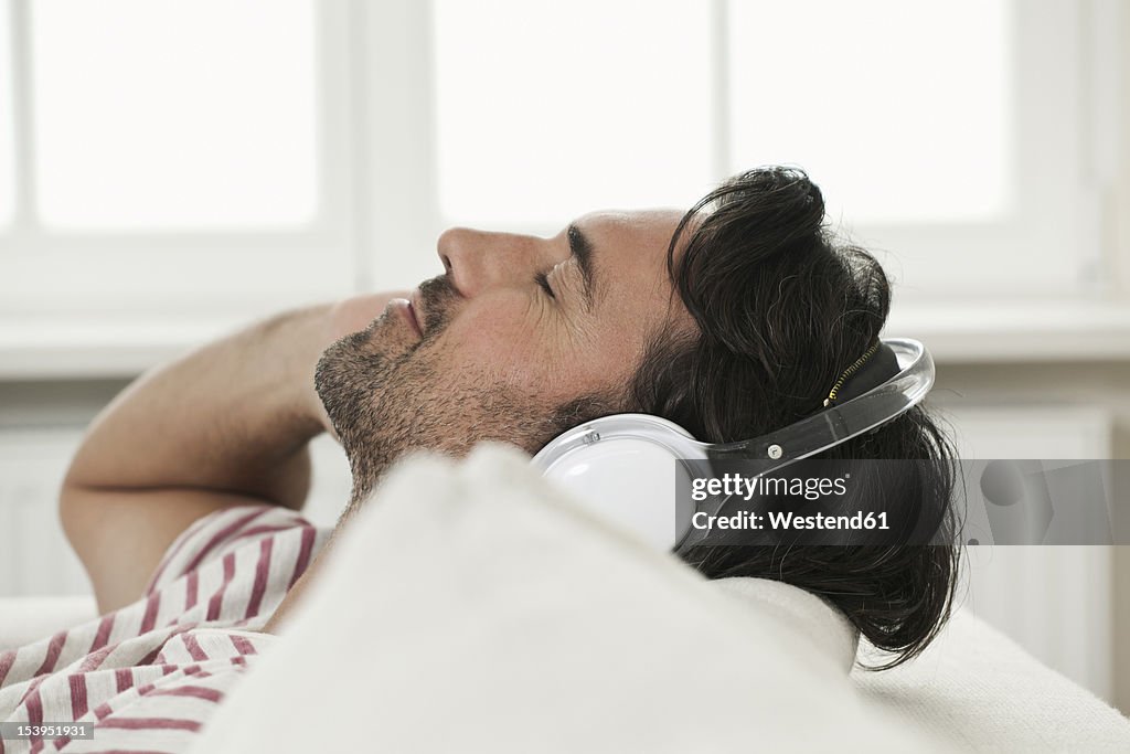 Germany, Berlin, Mature man listening music with head phones