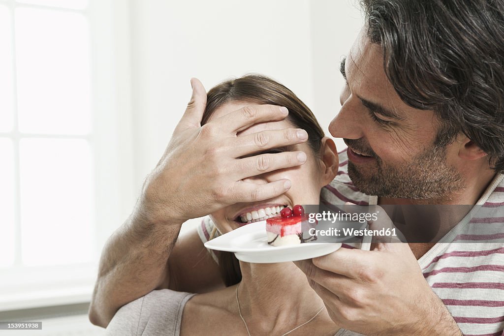 Germany, Berlin, Man surprising woman with serving cake