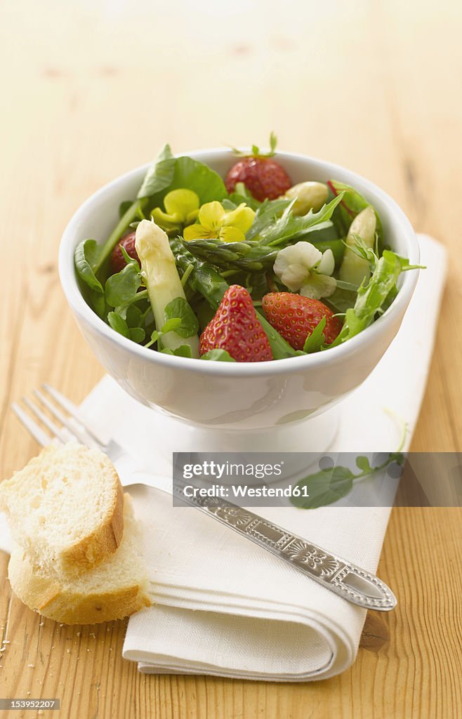 Bowl of wild herbs salad with asparagus and strawberries