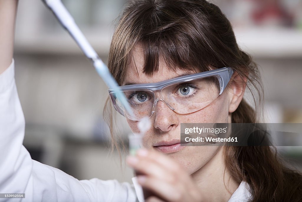 Germany, Bavaria, Munich, Scientist with pipette and test tube in laboratory