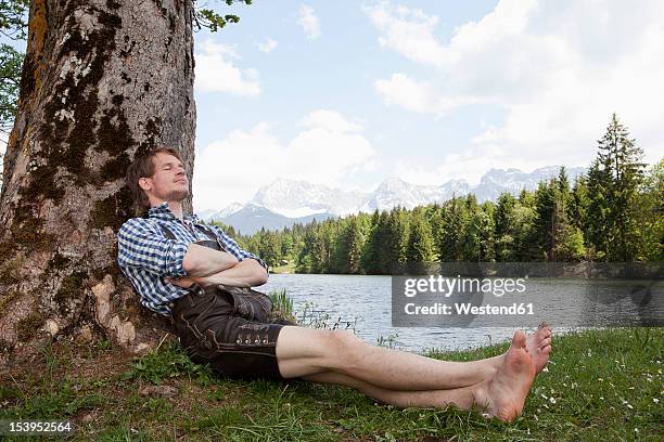 germany, bavaria, mid adult man relaxing under tree - bayern menschen stock-fotos und bilder