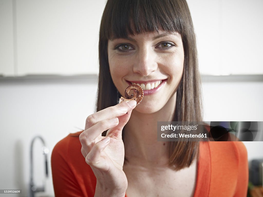 Germany, Cologne, Mid adult woman holding octopus tentacle, smiling, portrait