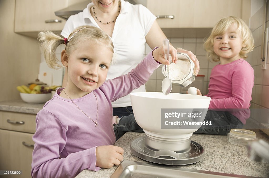 Mother and daughter preparing cake in kitchen