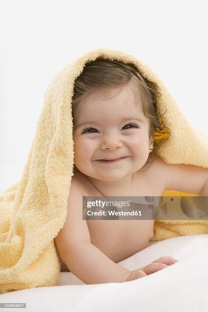 Baby girl with yellow blanket, smiling, portrait