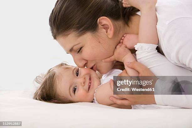 mother cuddling daughter, smiling - baby studio shot stock pictures, royalty-free photos & images