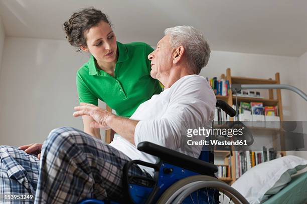 germany, leipzig, man on wheelchair, talking with woman - care stock-fotos und bilder