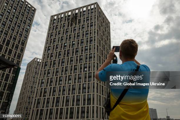 Man takes a photo of a 13-story residential building in Darnytskyi district of the city damaged by a downed Shahed kamikaze drone on July 13, 2023 in...
