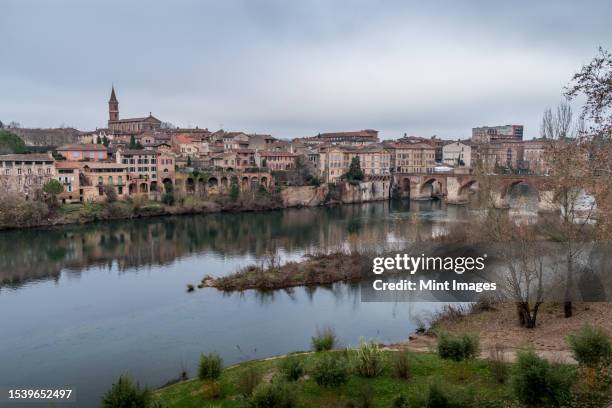 view of albi, the city and historic buildings from the river tarn, the pont vieux and an island in the stream - vieux stock pictures, royalty-free photos & images